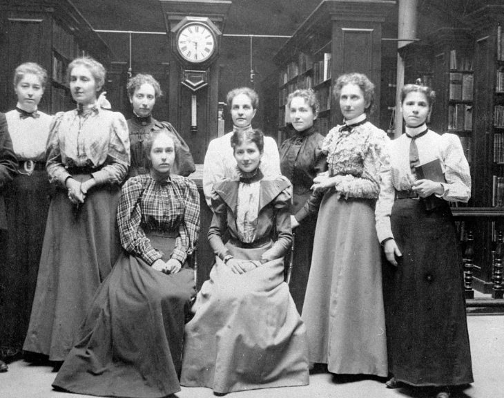women posing  inside library space.