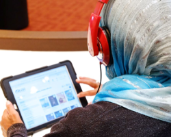A person wearing headphones is listening to an audiobook on a tablet.
