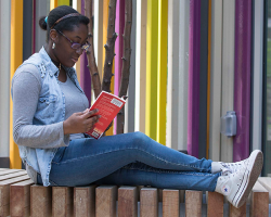 A person is reading a book outside of a library branch.