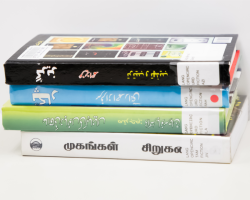 a stack of books written in Tamil and Urdu