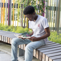 A teen reads outside the library