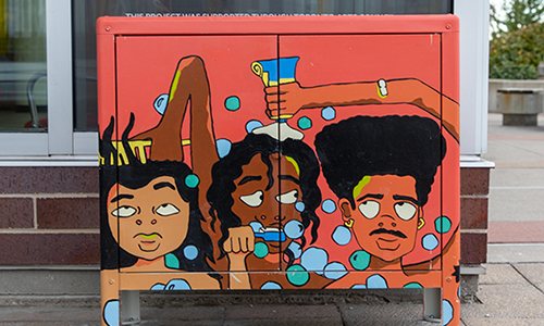Cabinet outside the branch with painting art of three young men doing different personal care activities including brushing and washing hair and brushing teeth.